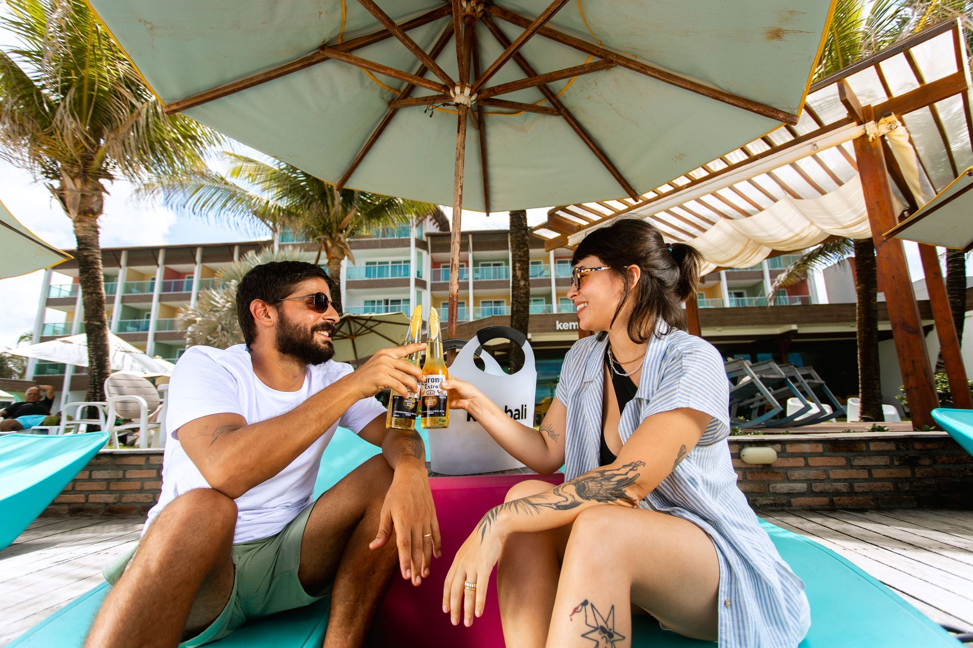 Casal brindando momentos especiais em área de lazer à beira-mar, em clima descontraído e acolhedor.
