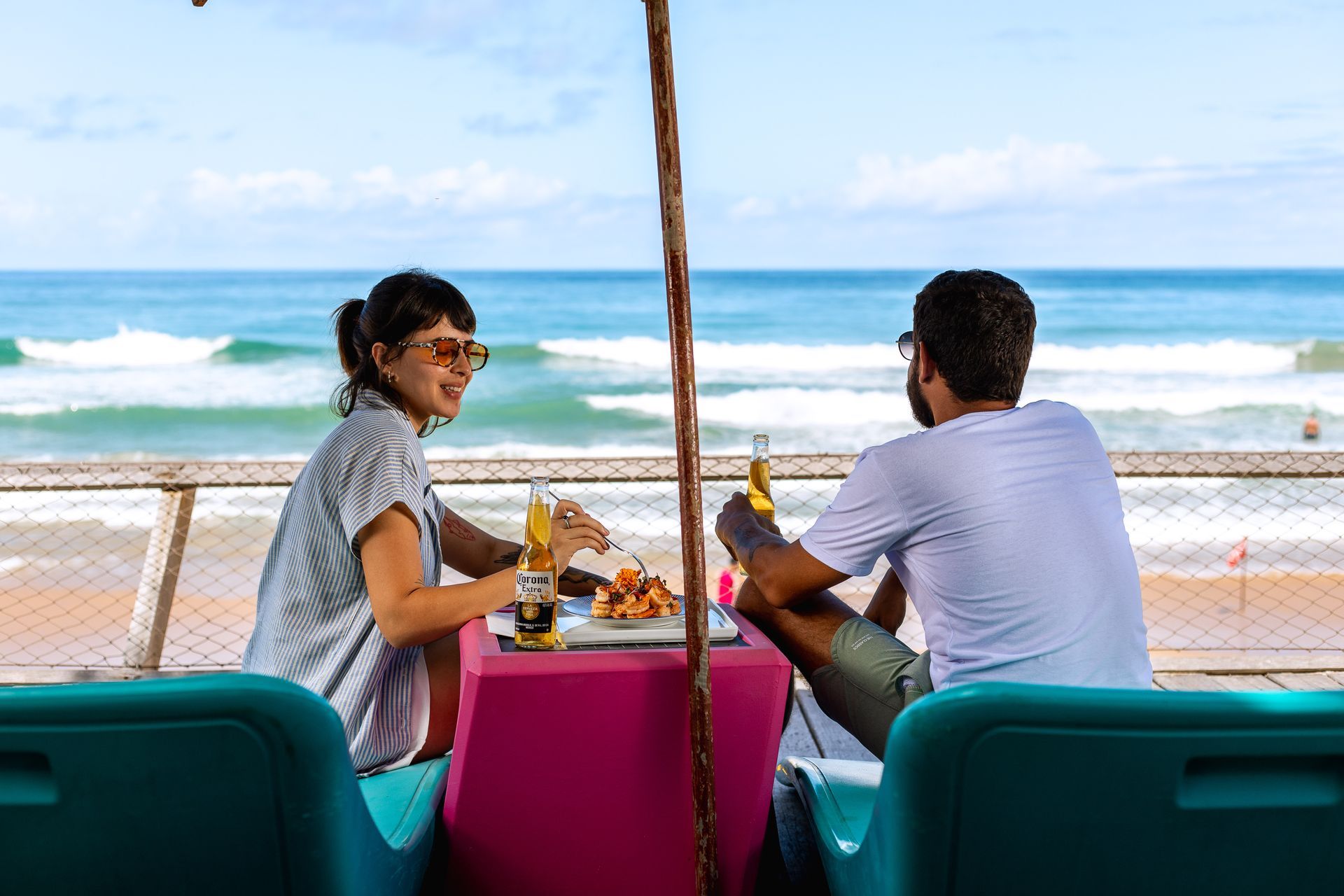 Casal a à beira-mar em Porto de Galinhas, com vista para a praia e o mar em um cenário de descanso e gastronomia.