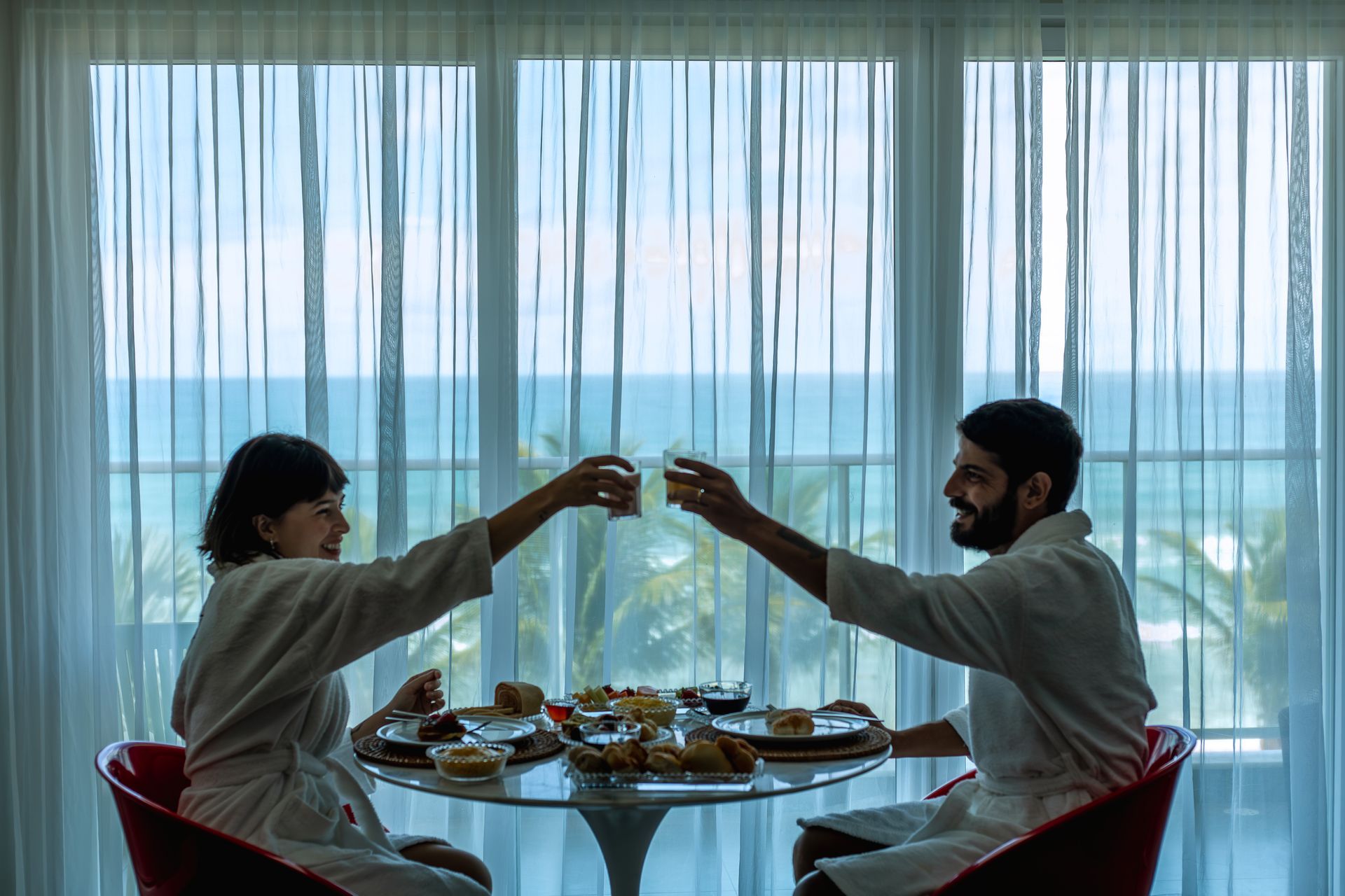 Casal desfruta de um café da manhã com vista para o mar em uma hospedagem à beira-mar.