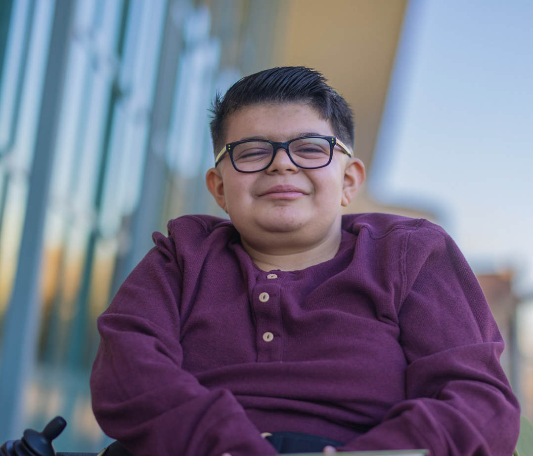 A young man in a wheelchair is smiling.