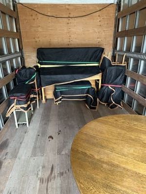 Furniture wrapped in black covers with colorful tape inside a moving truck.