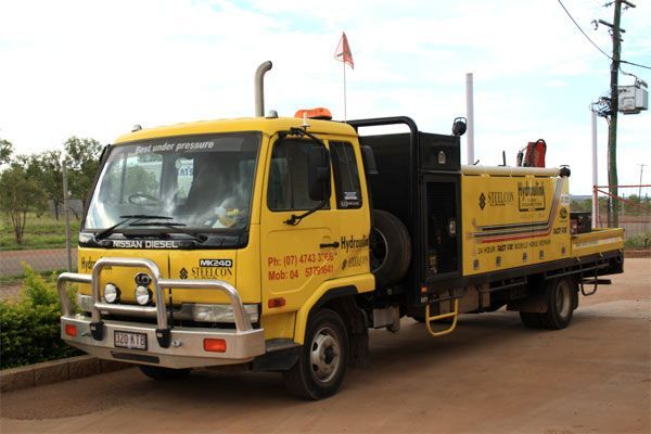 A yellow truck is parked on the side of the road