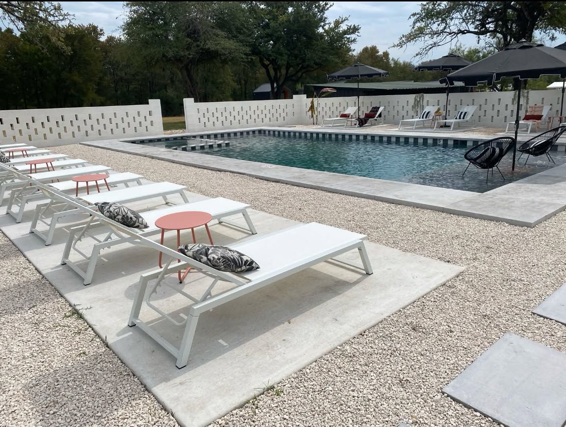 Outdoor pool deck with white lounge chairs and an elevated rectangular pool with umbrellas