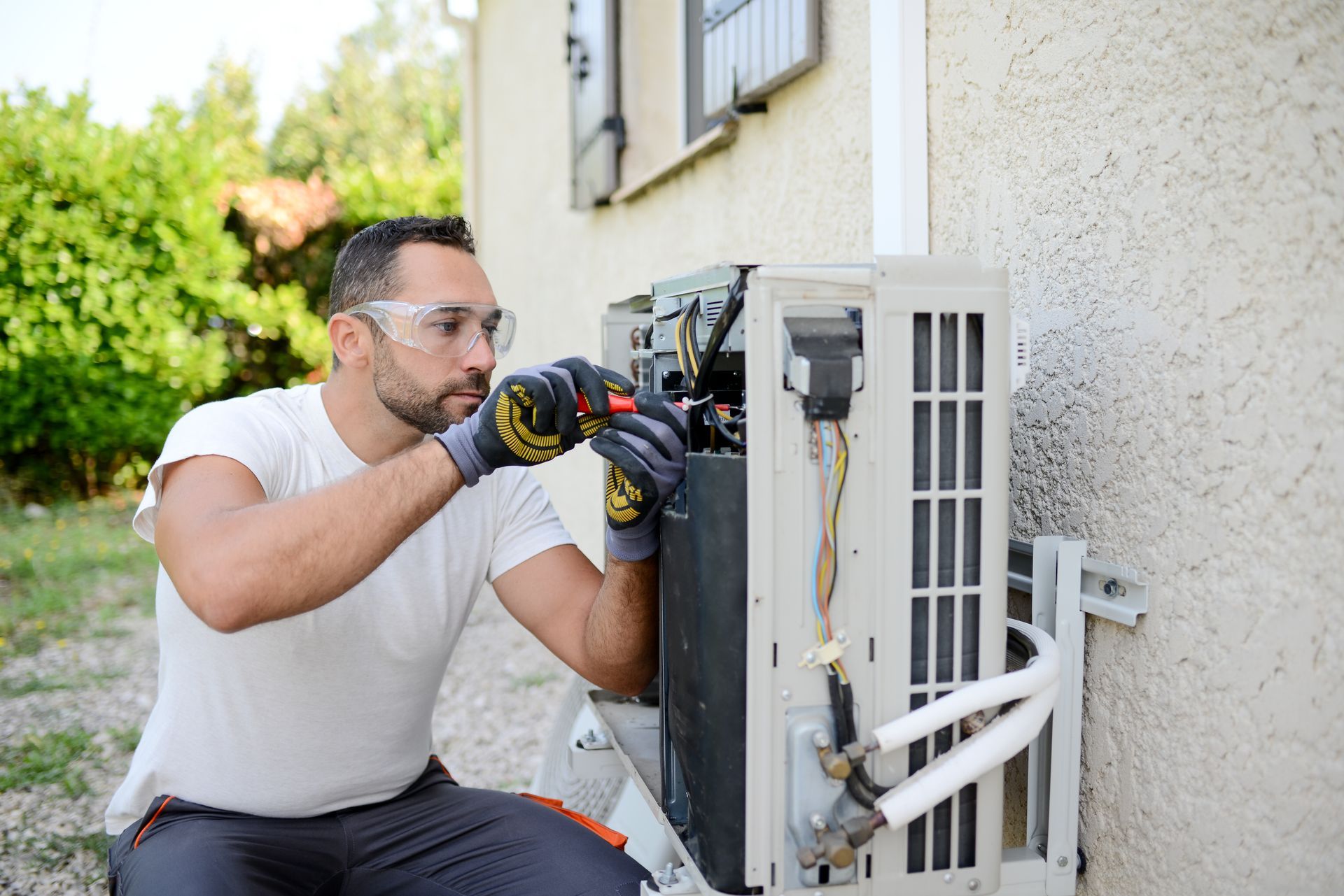 Gloved technician connects wiring inside a unit during a residential air conditioning installation.