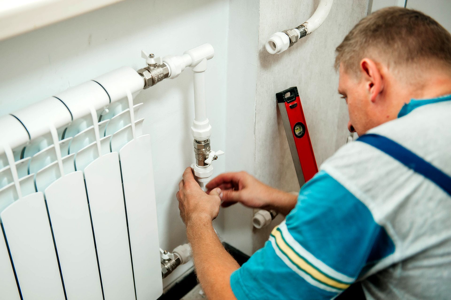 Plumber works on a white radiator.