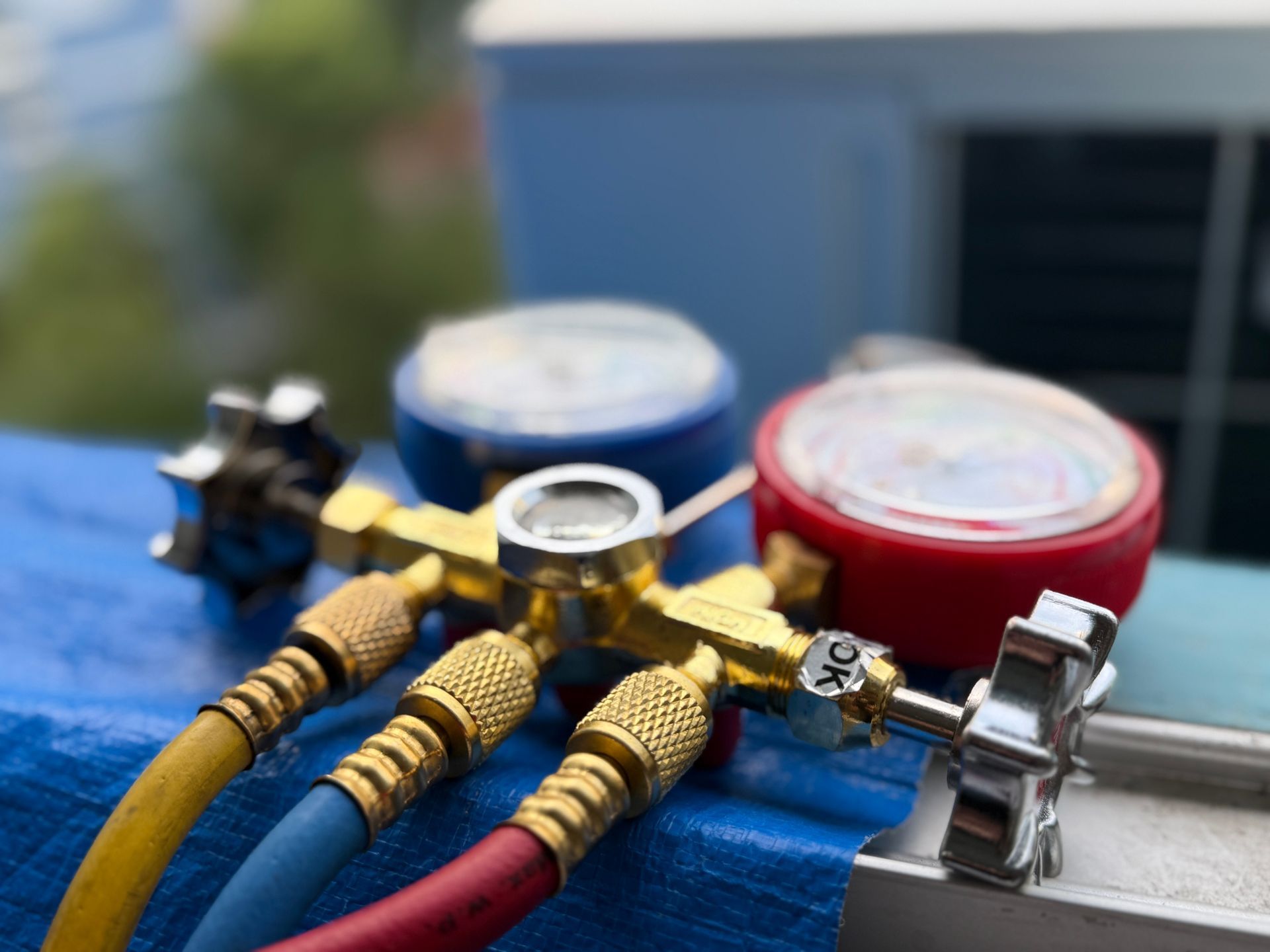 Close-up of HVAC manifold gauge set with colored hoses.