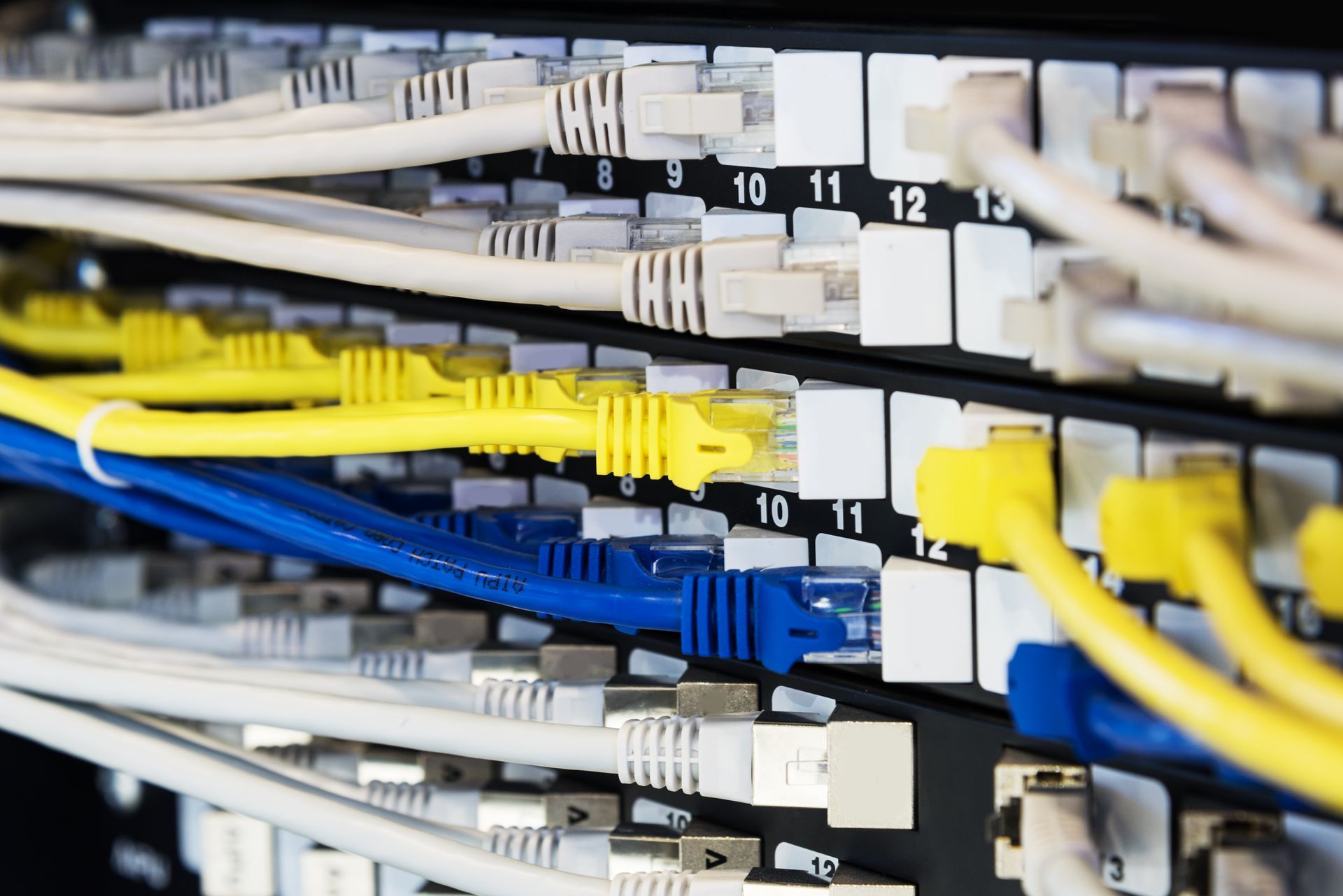 File di cavi Ethernet gialli, blu e bianchi collegati a uno switch di rete in un data center.