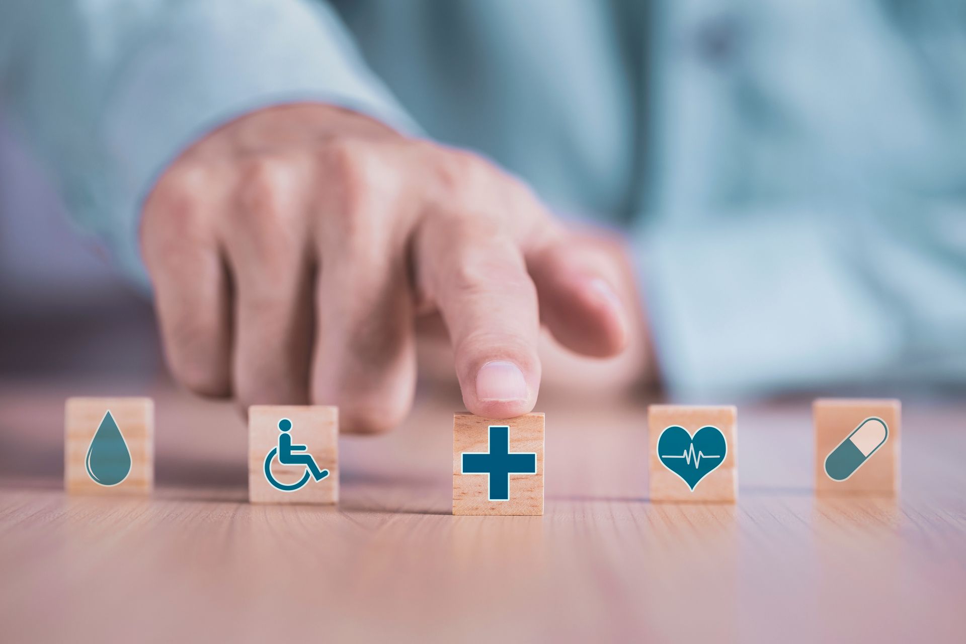 A person is holding a wooden block with a medical icon on it.