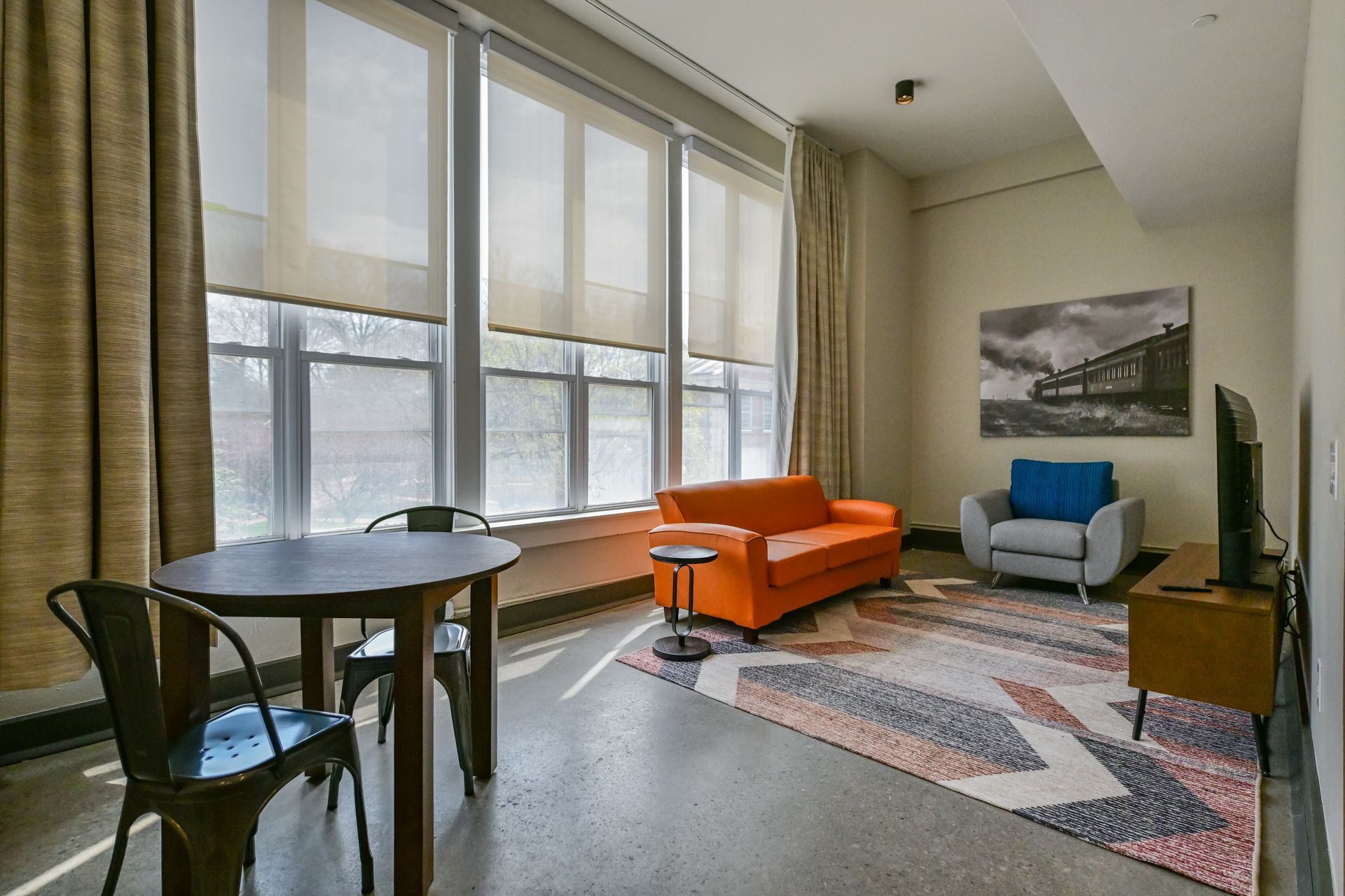 A bedroom with two beds , a chair , a desk and a window.