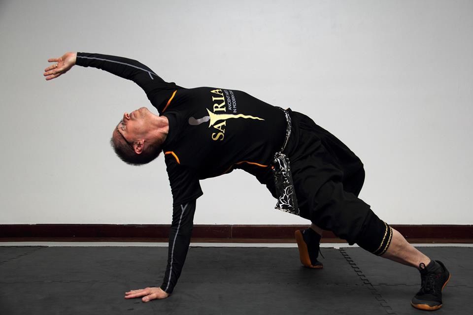 A man wearing a shirt that says samurai is doing a plank