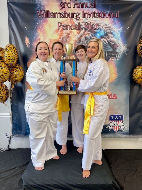 A group of women holding a trophy in front of a banner that says 3rd annual williamsburg invitational