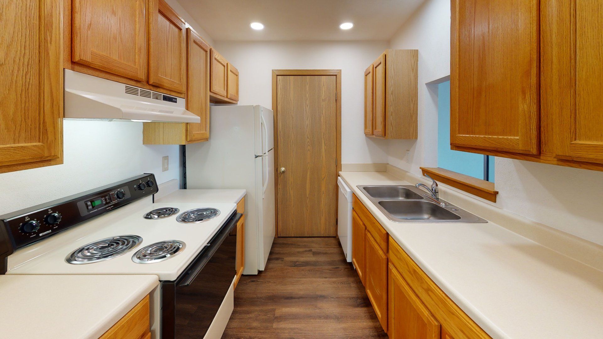 A kitchen with a stove , refrigerator , sink and cabinets.