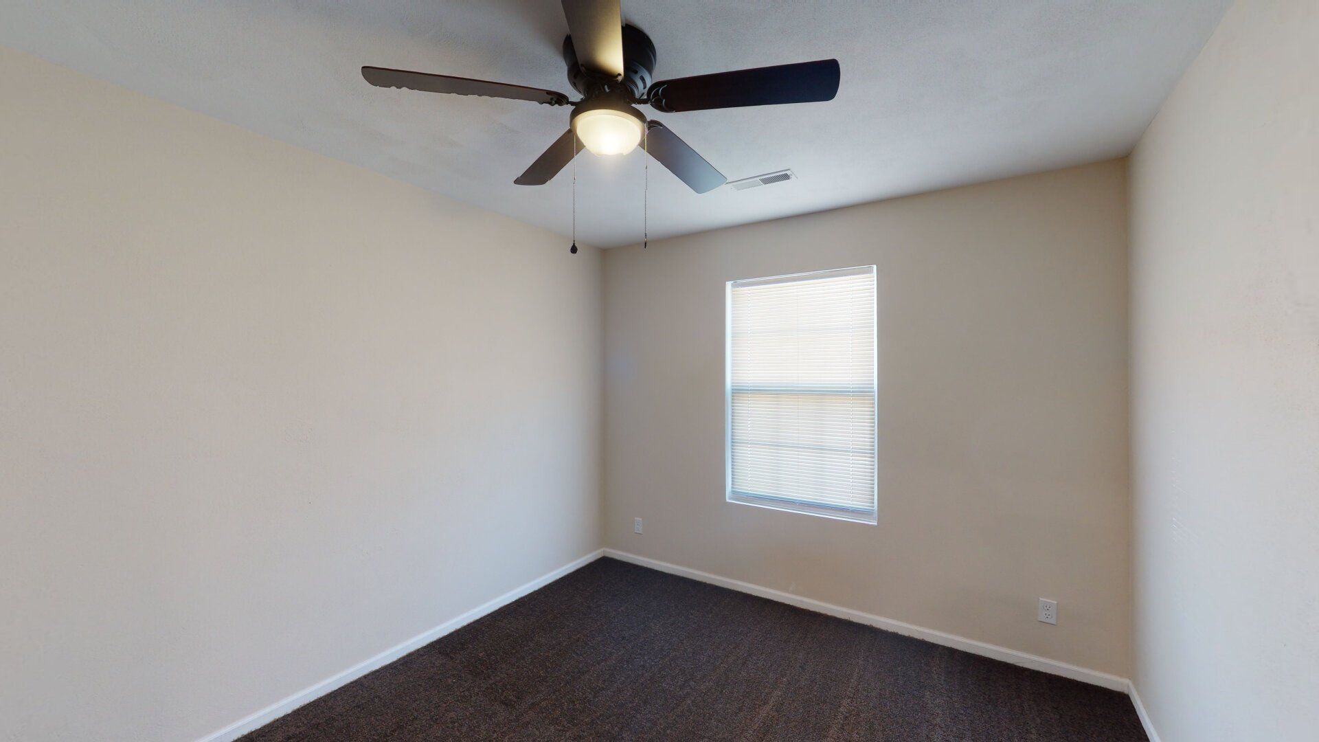 An empty bedroom with a ceiling fan and a window.