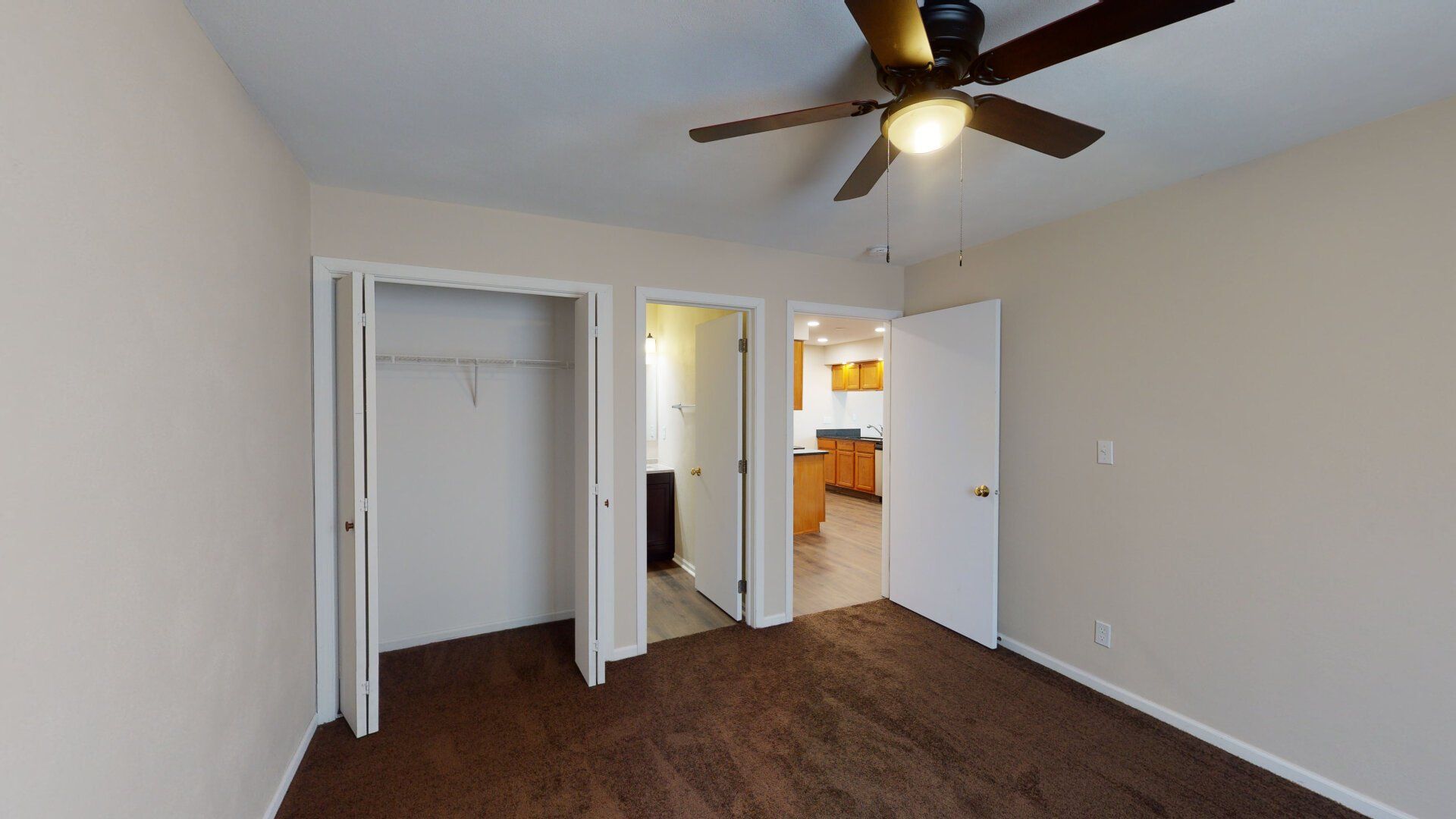 An empty bedroom with a ceiling fan and a closet.