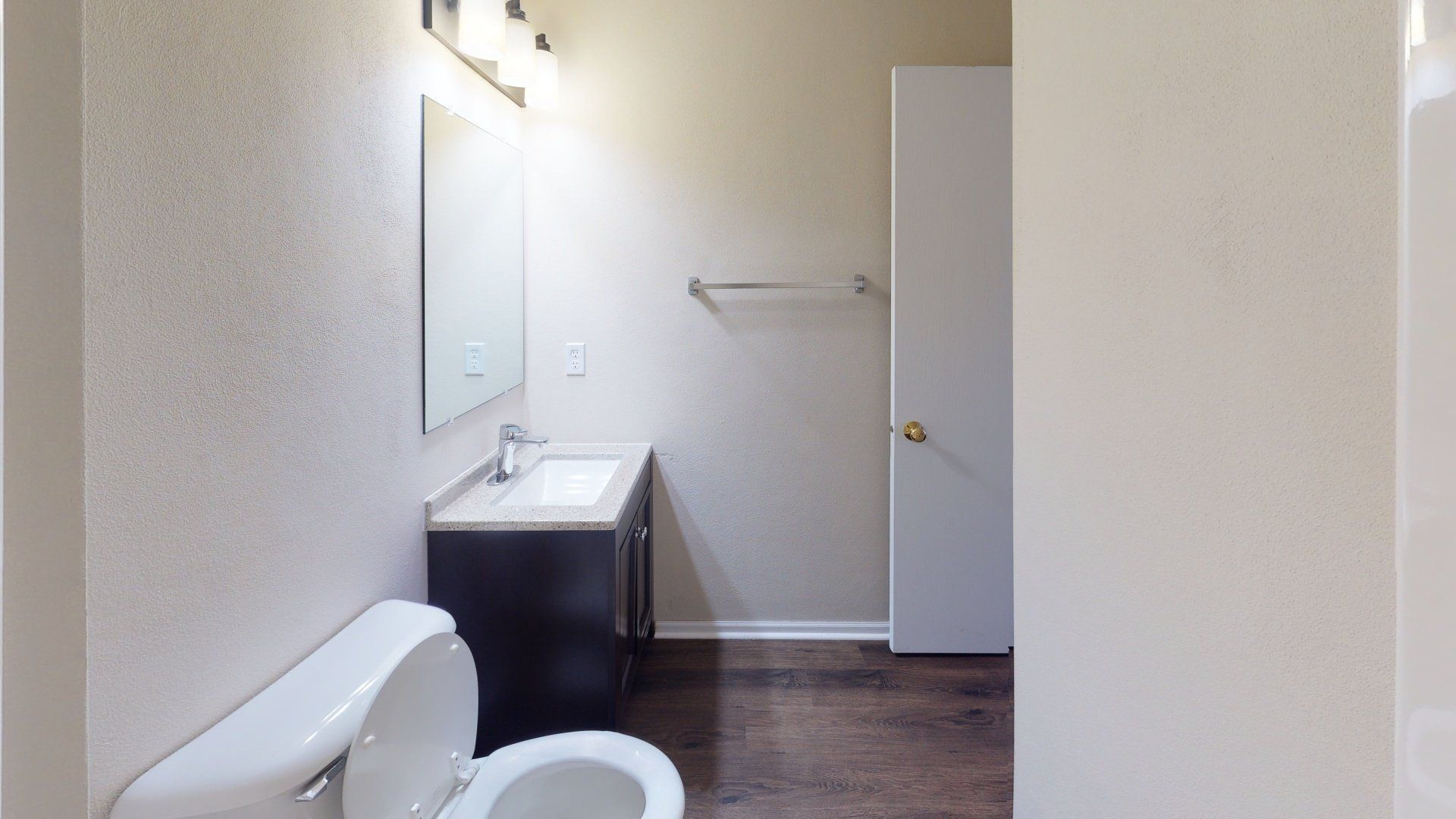 A bathroom with a toilet , sink and mirror.