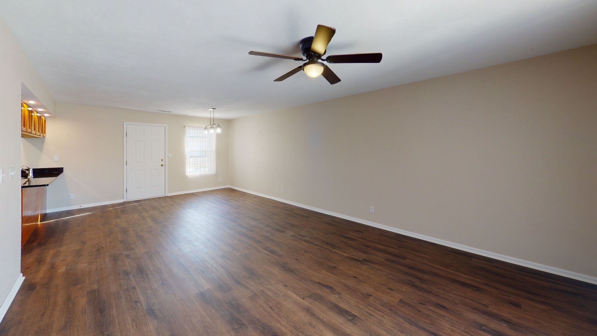 An empty living room with hardwood floors and a ceiling fan.