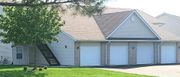 A house with three garage doors and a tree in front of it.