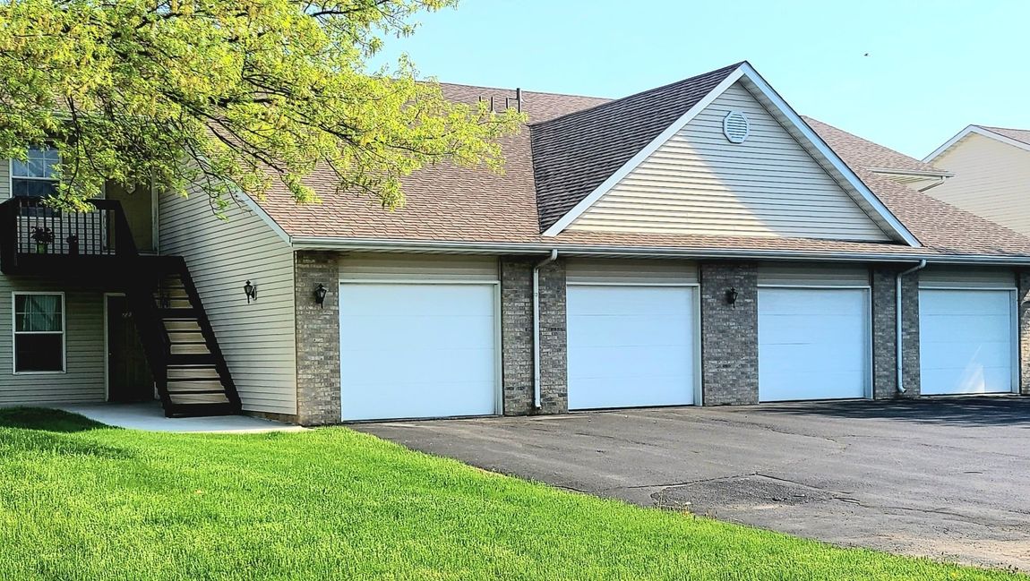 A house with three garage doors and stairs in front of it