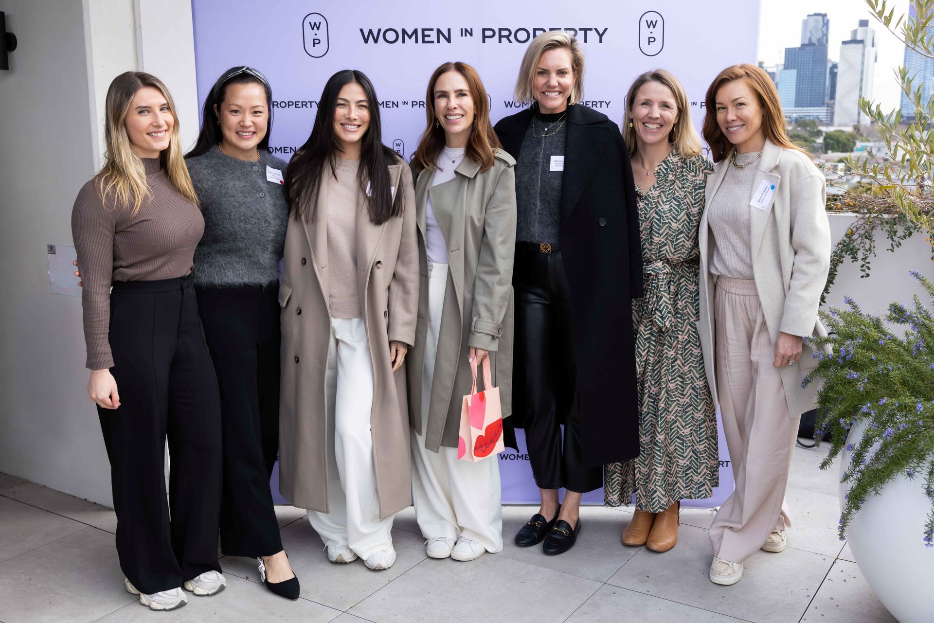 Seven people smiling in professional attire stand before a