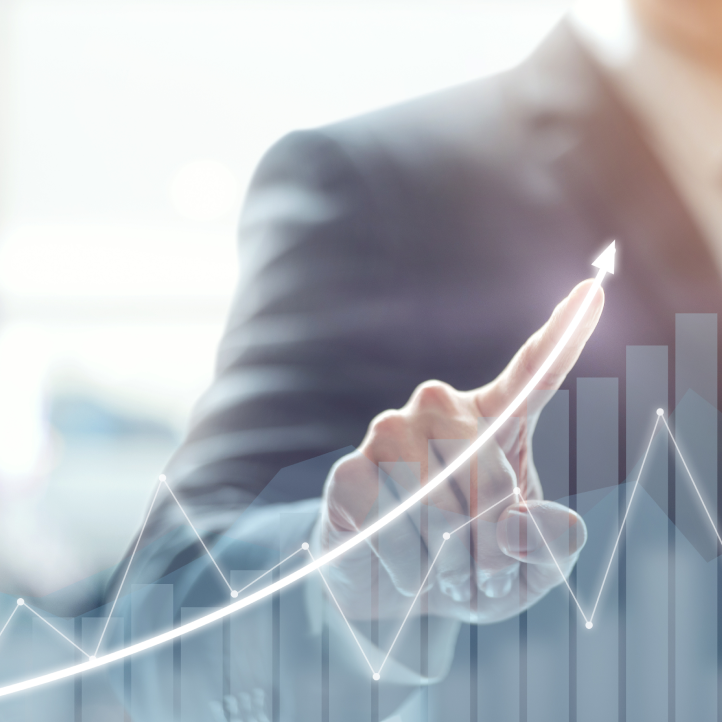 A business professional pointing at a glowing, upward-trending stock market graph overlay.