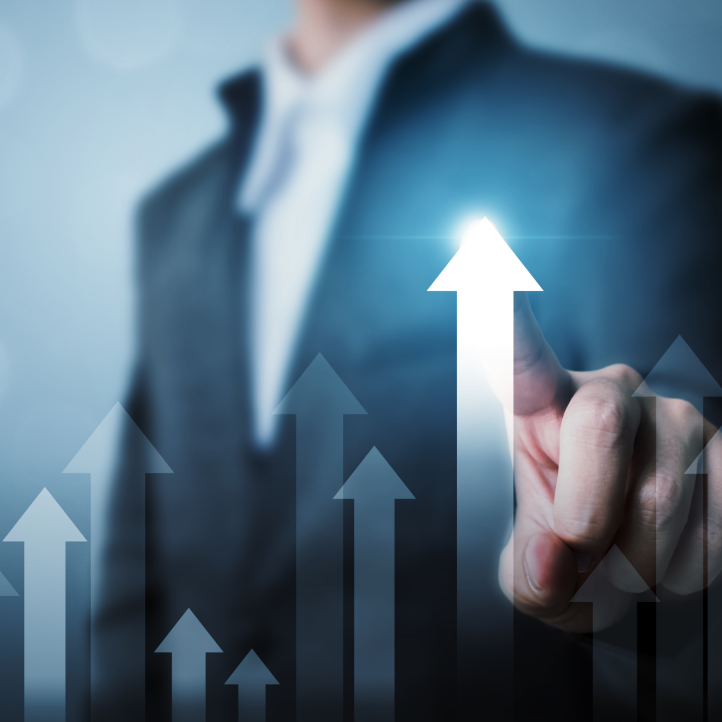 A person in a suit points to a glowing, upward-trending arrow, symbolizing growth and business success.
