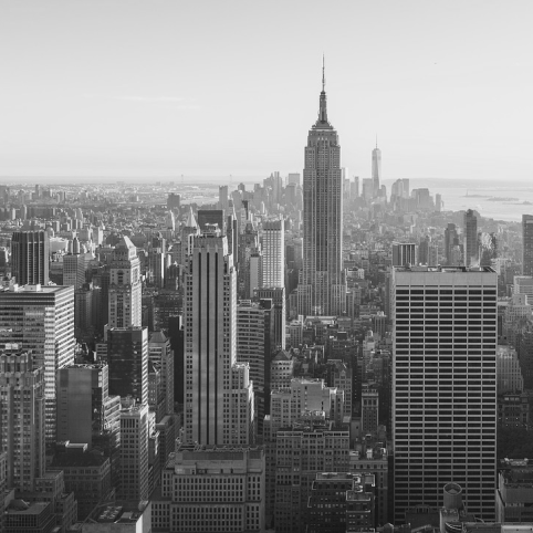 A high-angle, black-and-white cityscape view of New York City, dominated by the Empire State Building.