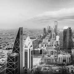 Black and white high-angle view of the Riyadh skyline, featuring the Kingdom Centre and modern skyscrapers.