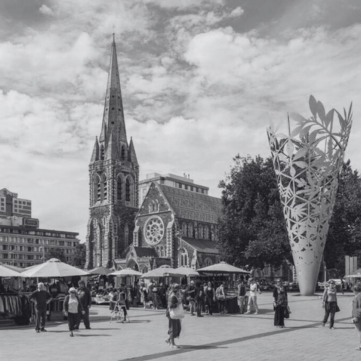Christchurch Cathedral stands tall in a busy city square with market stalls and the tall, metallic Chalice sculpture nearby.