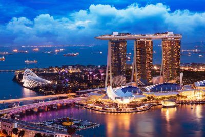 Marina Bay Sands resort with its three iconic towers and connecting rooftop, overlooking Singapore at twilight.