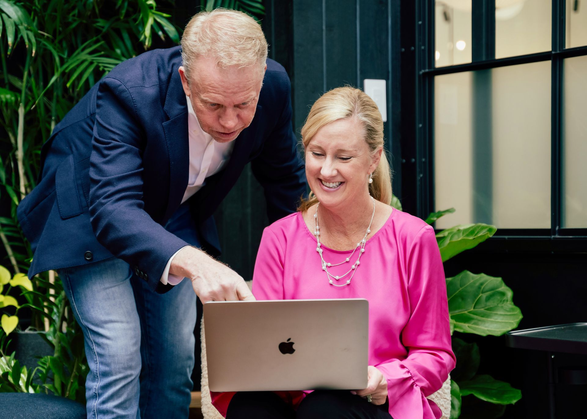 A man and a woman are looking at a laptop computer.