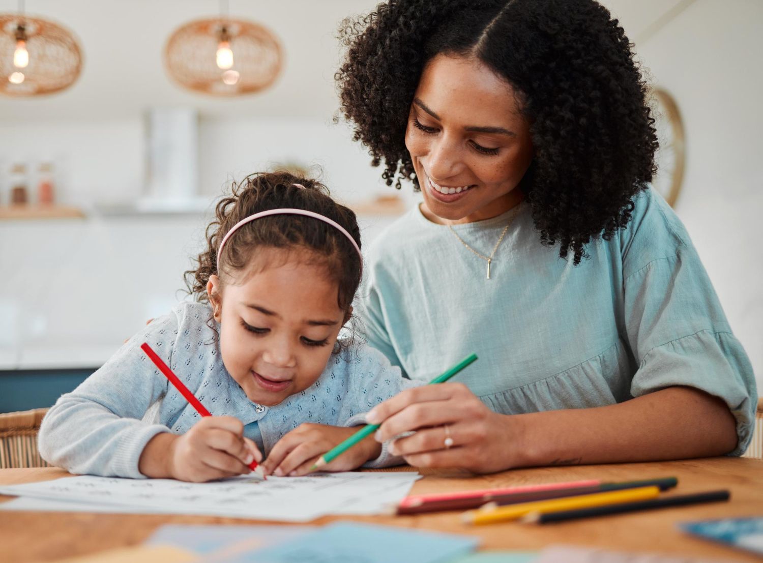Woman assisting a child with coloring at a table indoors.