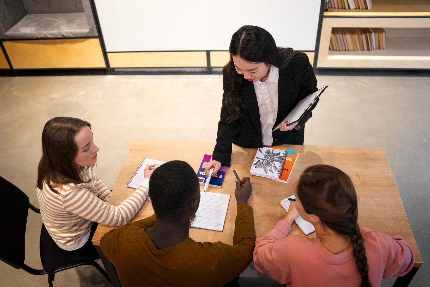 Woman leading a meeting with three colleagues at a table, pointing at materials.
