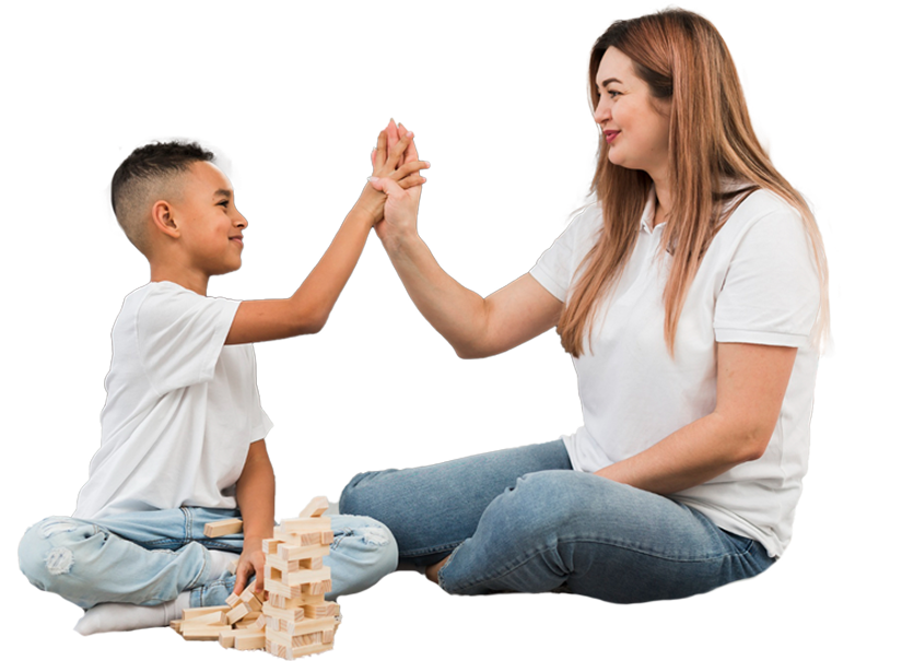 A child and an adult high-fiving while sitting on the floor with wooden blocks.