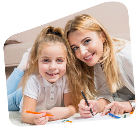 Woman and child smiling and drawing together on a rug.