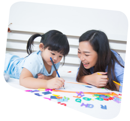 Woman and child drawing together on a bed; colorful alphabet letters are scattered around them.