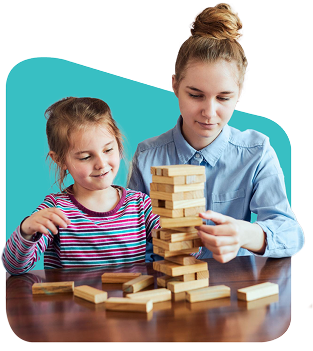 Woman and child playing Jenga, wooden tower on table. Child smiles, woman focuses on game.