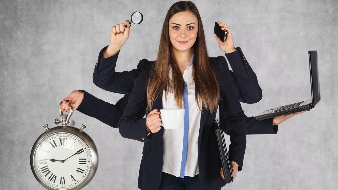 A woman with many hands is holding a clock , a cup of coffee , a cell phone , and a laptop.
