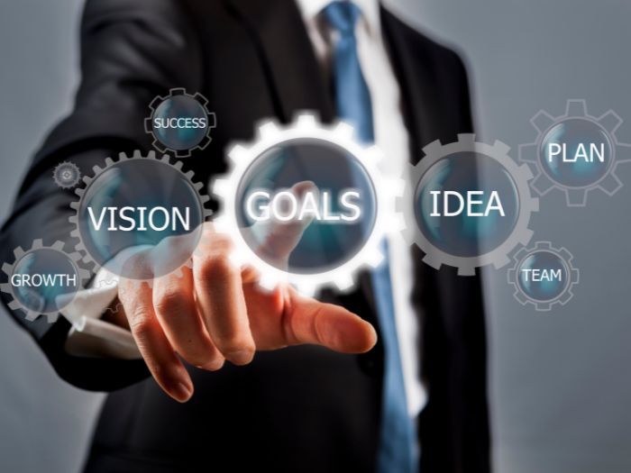 A man is pressing a button that says vision goals idea and plan