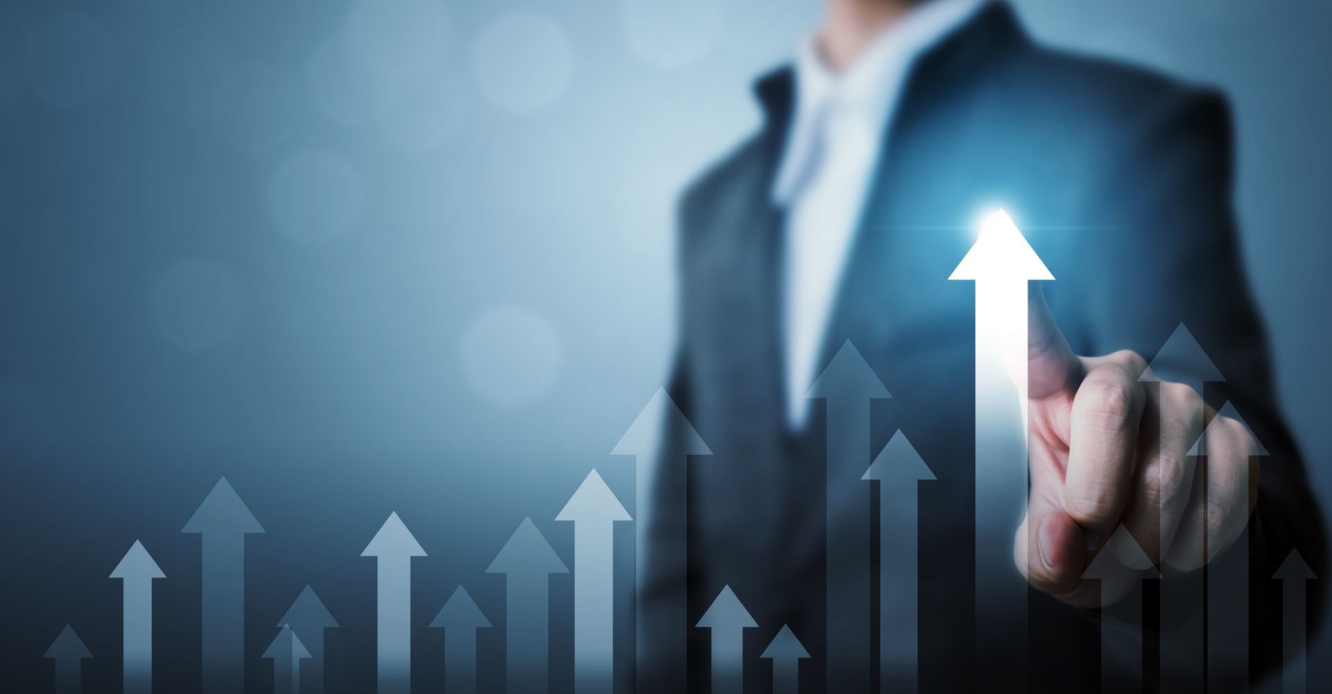 A man in a suit is pointing at an arrow that is going up.