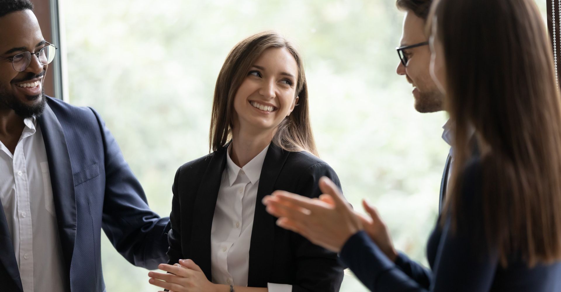 A group of business people are standing around talking to each other.