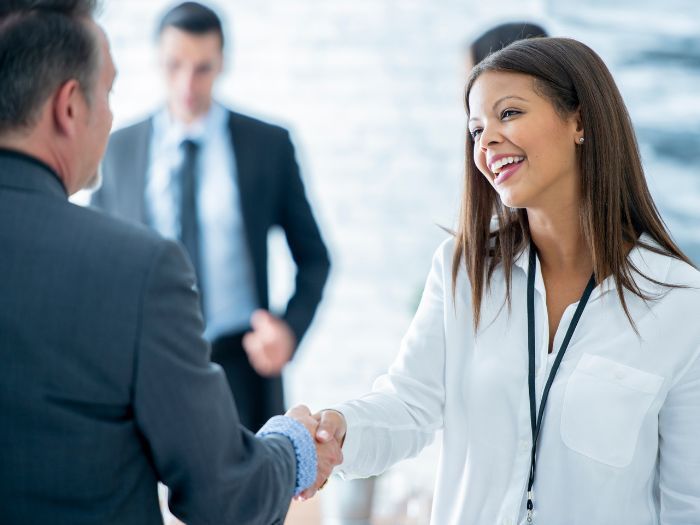A woman in a white shirt is shaking hands with a man in a suit.