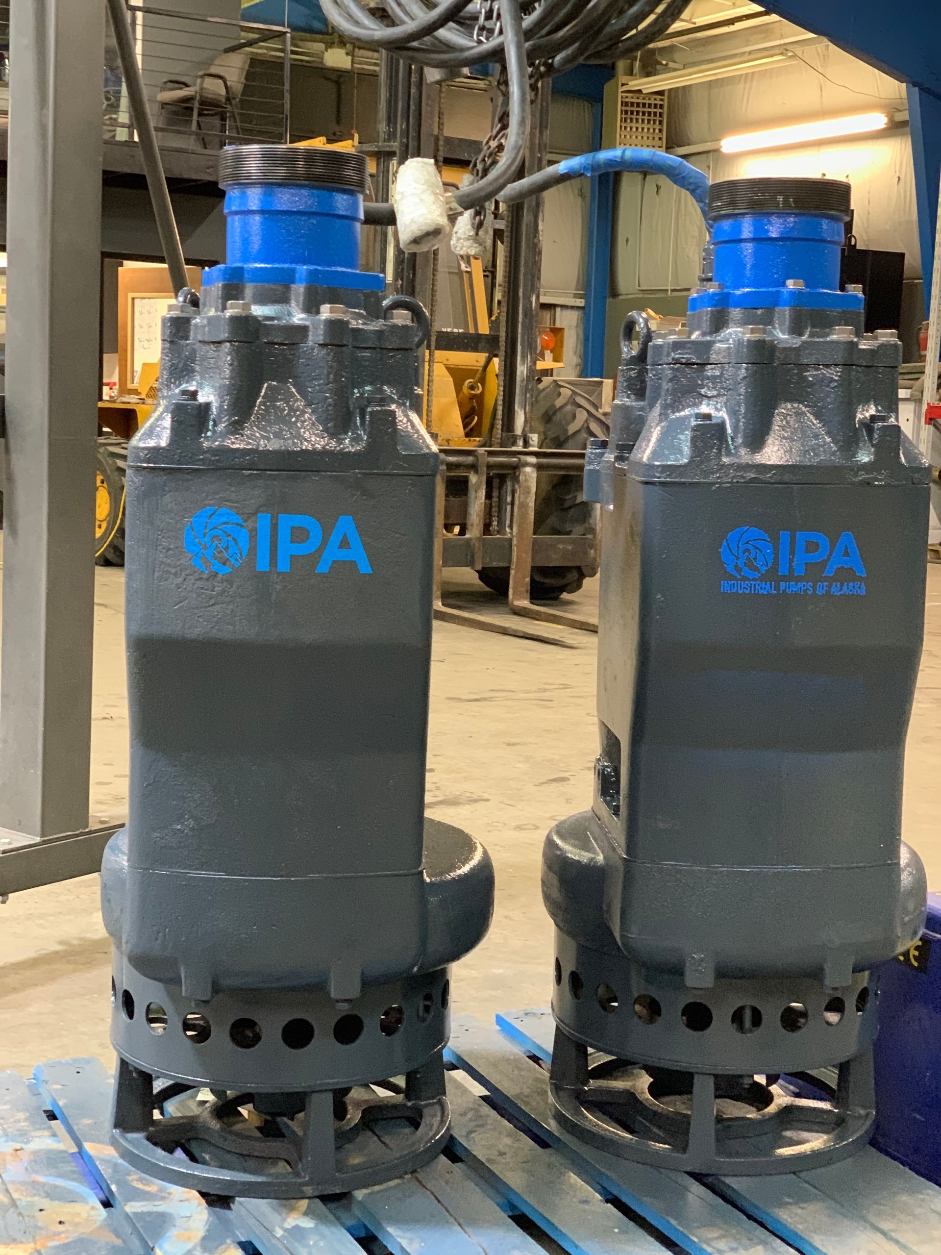 Two pumps are sitting on a pallet in a factory.