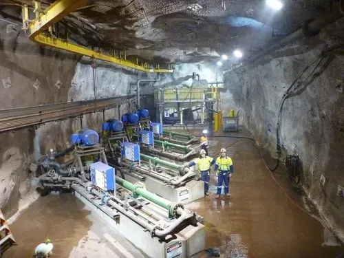 A group of people are standing in a large room in a cave.