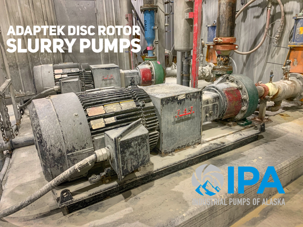 A large motor is sitting in a room next to a pump.