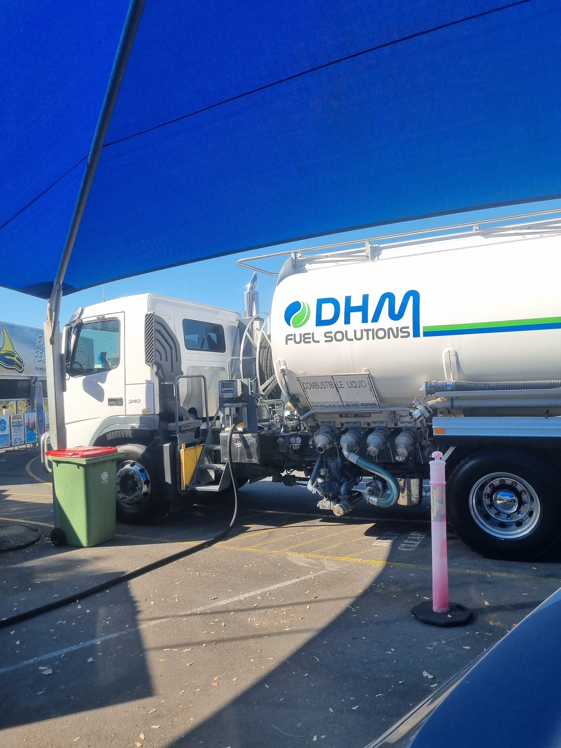 Fuel tanker truck parked under a blue shade, with