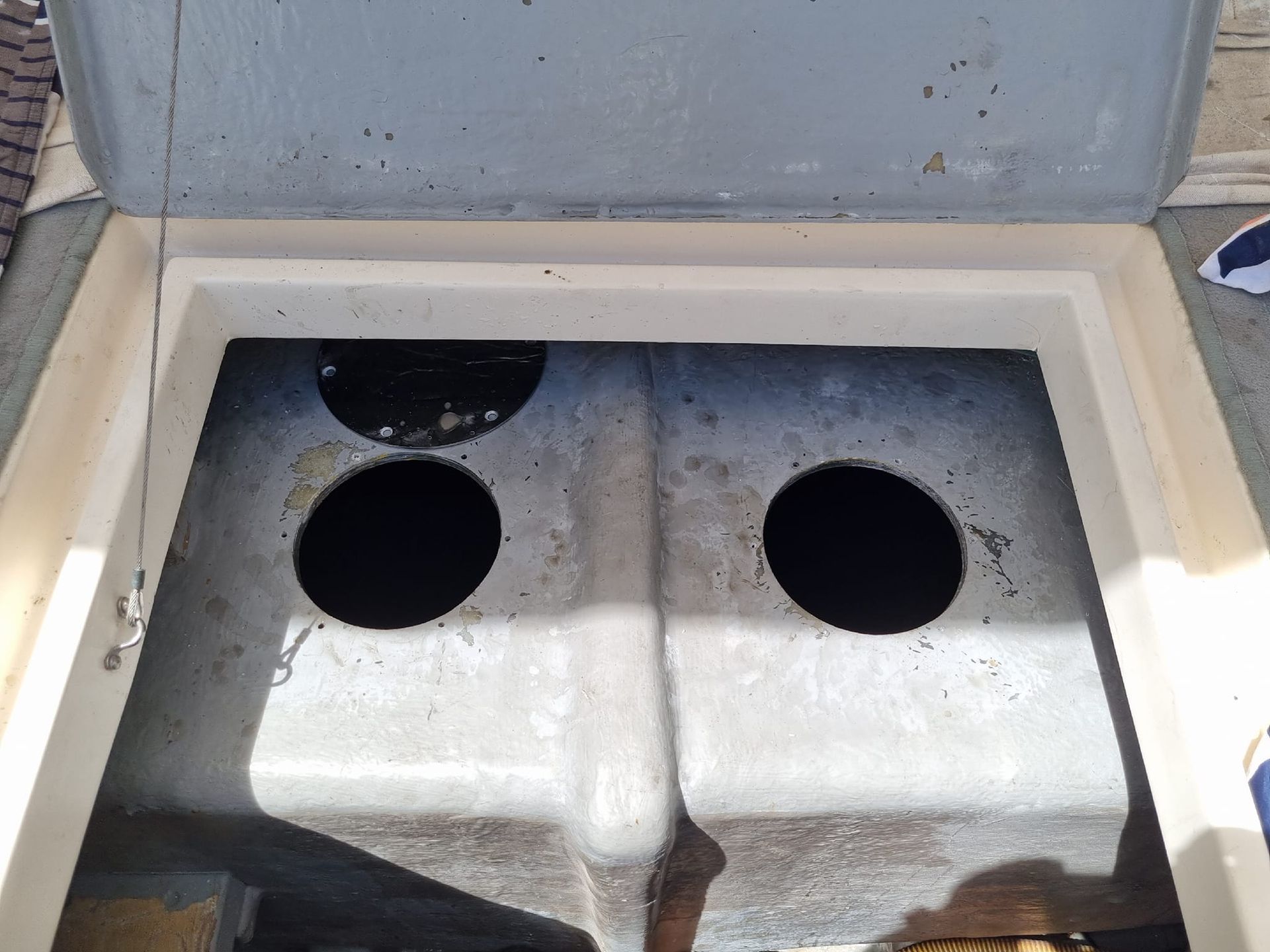 Close-up of a white metal compartment with four circular holes and a gray interior panel.