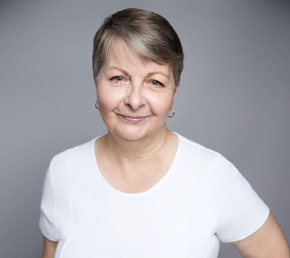 A woman with long brown hair is wearing a white shirt and black pants.