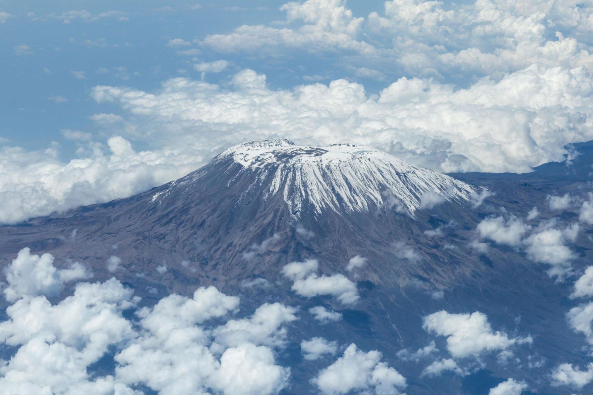Snow-capped mountain above a sea of clouds under a blue sky