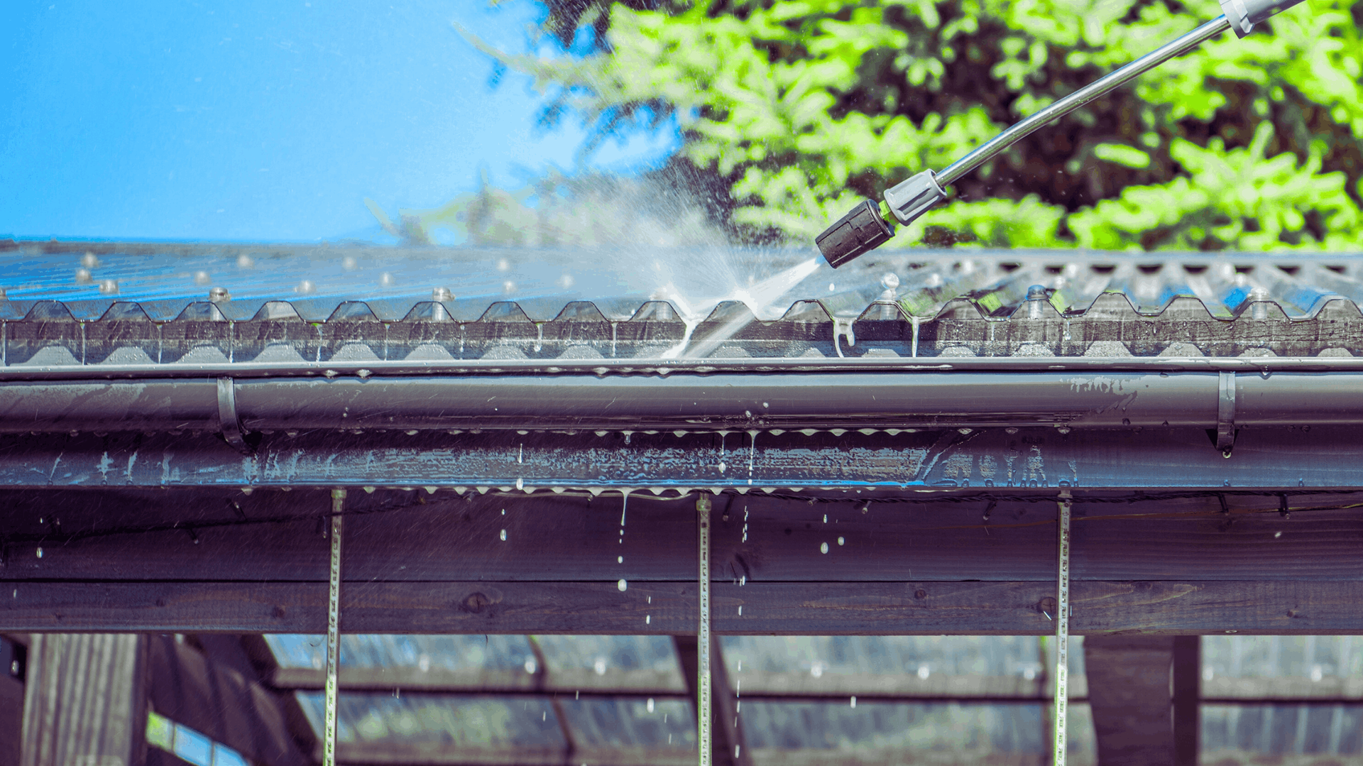 Pressure washer cleaning a dark gutter, water spraying down — Rohan's Maintenance in Robina, QLD