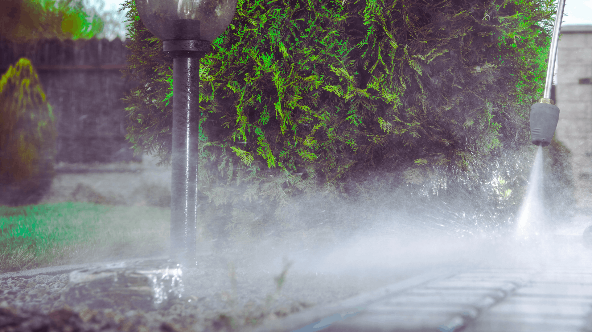 High-pressure washer spraying water on a brick path, creating mist — Rohan's Maintenance in Robina, QLD
